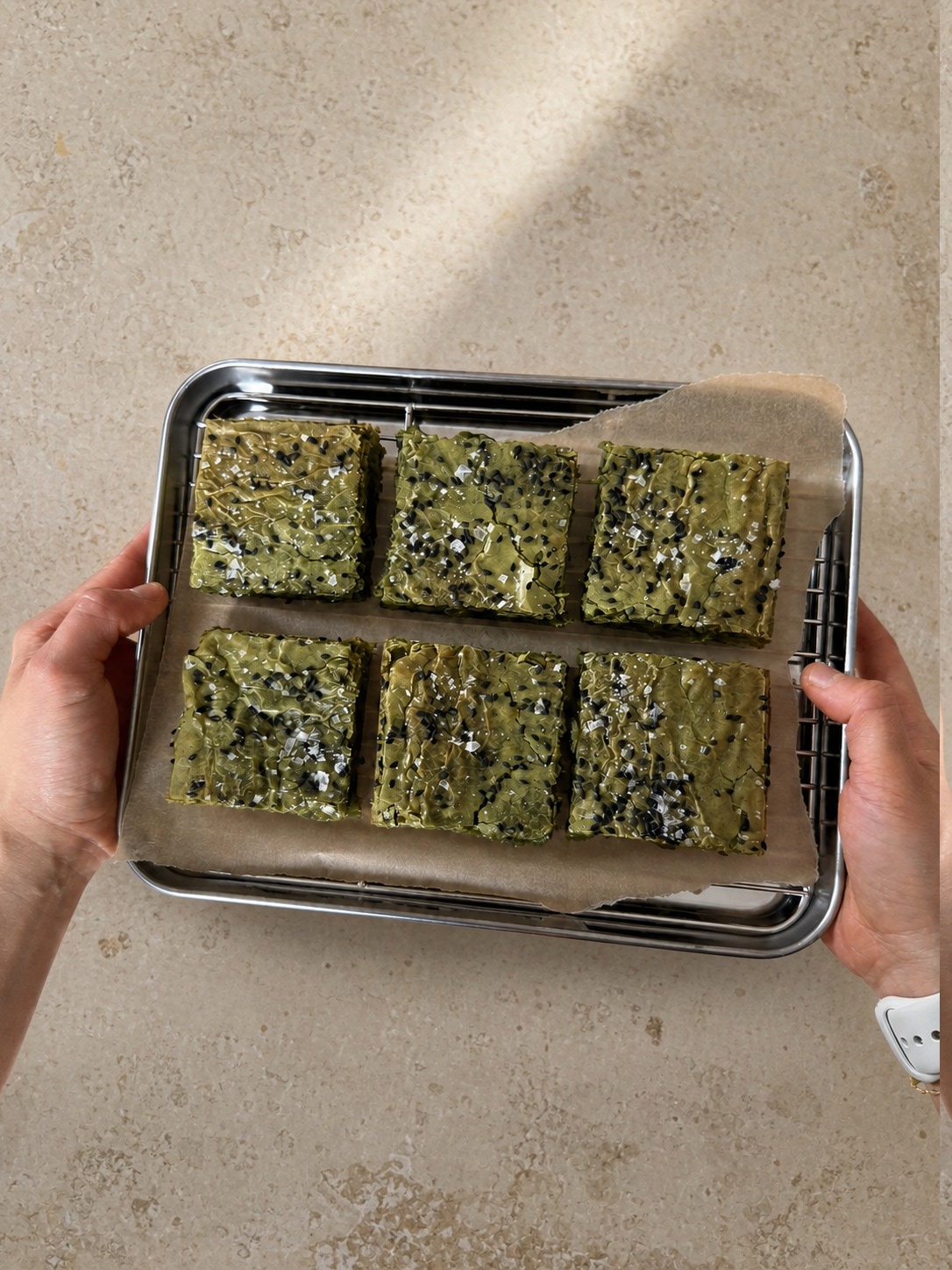 Six matcha brownies on a tray held in two hands