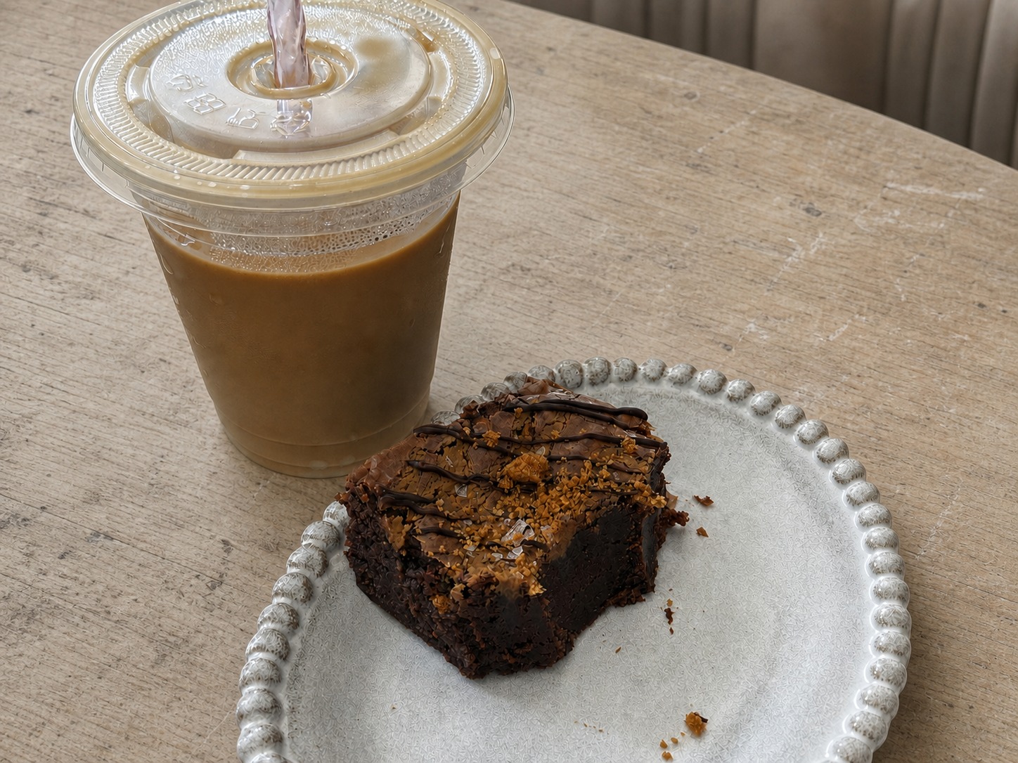 Miso Biscoff brownie on a plate beside an iced drink